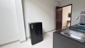 A modern kitchen with a black refrigerator, a stainless steel sink, and a wooden door leading to another room. - Sekar Tunjung Guest House Seminyak Bali (Denpasar)