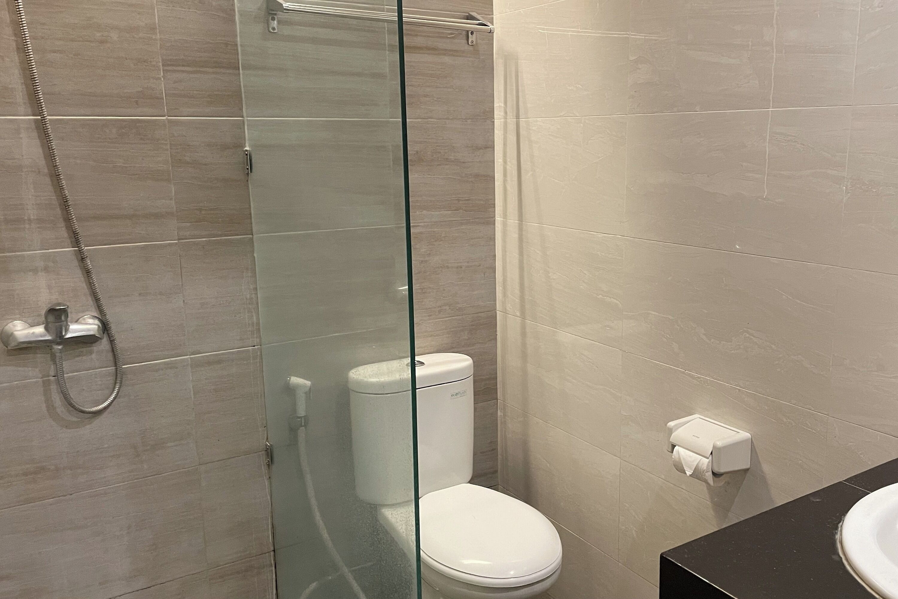 A modern bathroom with a glass-enclosed shower, a white toilet, and a black countertop with a sink.