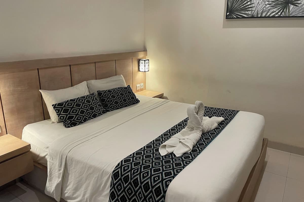 Un lit bien fait, avec une couverture à motifs, un oreiller et une serviette posés sur le lit.