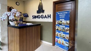 A reception desk with a sign reading "SINGGAH" and a menu board for the Singgah Eatery. - Singgah Hotel Seminyak (Seminyak)