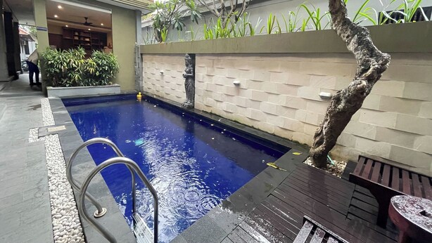 An indoor swimming pool with a clear water surface, surrounded by a tiled deck and a low brick wall. - Singgah Hotel Seminyak (Seminyak)