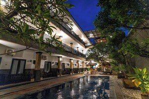 Ein Hotel mit Schwimmbad, Außenbereich mit Sitzgelegenheiten und einer überdachten Pflanzenecke.