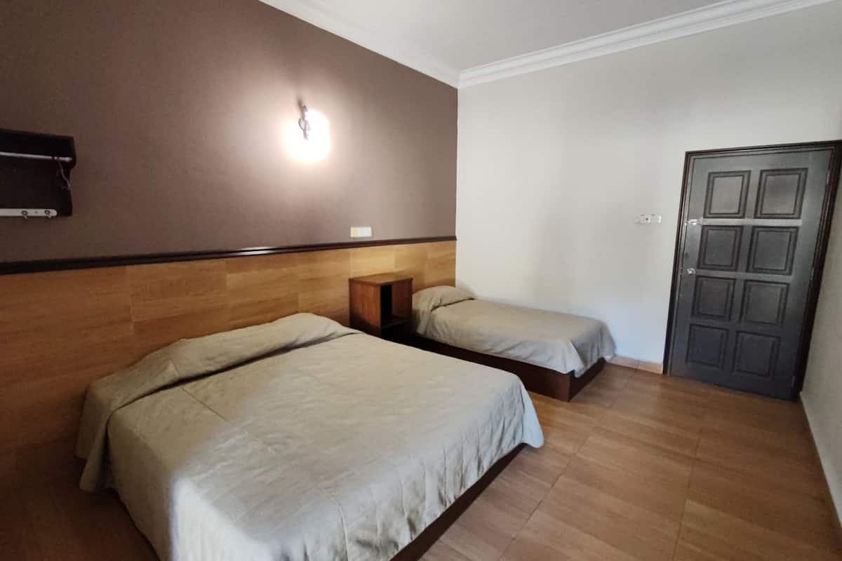 Une chambre d’hôtel avec deux lits, une tête de lit en bois, une table de chevet, une lampe fixée au mur et une porte.