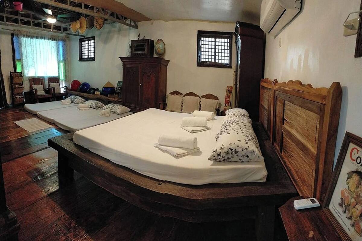A room with two beds, wooden headboards, a wardrobe, a globe, and a window with bars.