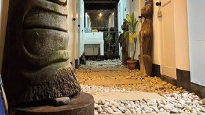 A hallway with a large stone sculpture, potted plants, and a pebbled floor. - Surfer'S Villa (San Juan)