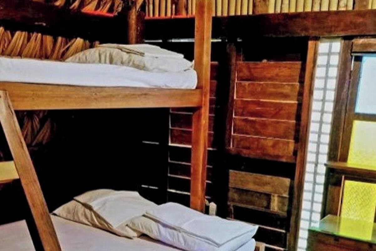 A bunk bed room with wooden walls and a small desk with a lamp.