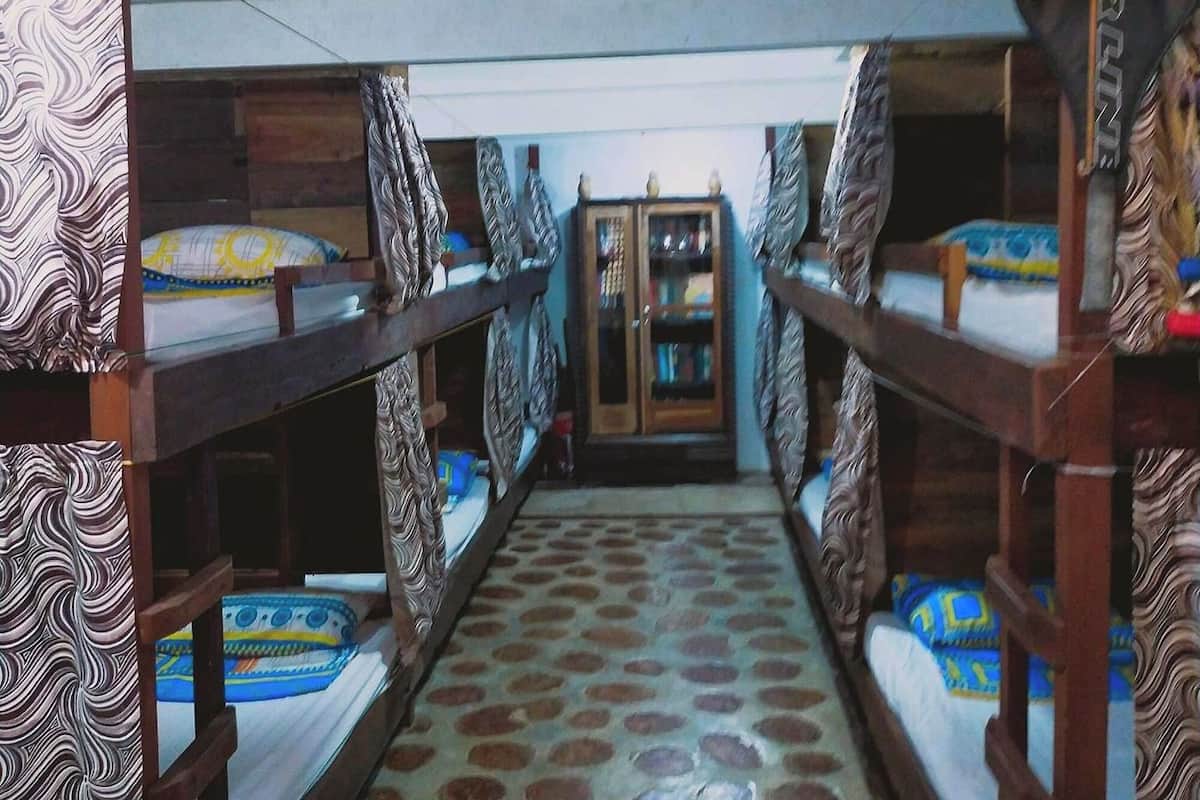 A row of bunk beds with patterned bedding, a patterned floor, and a door with a 'Prince' sign.