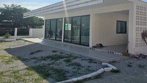 Un bâtiment moderne doté d’un toit plat, de grandes fenêtres en verre et d’un patio dallé agrémenté de gravier et de gazon.