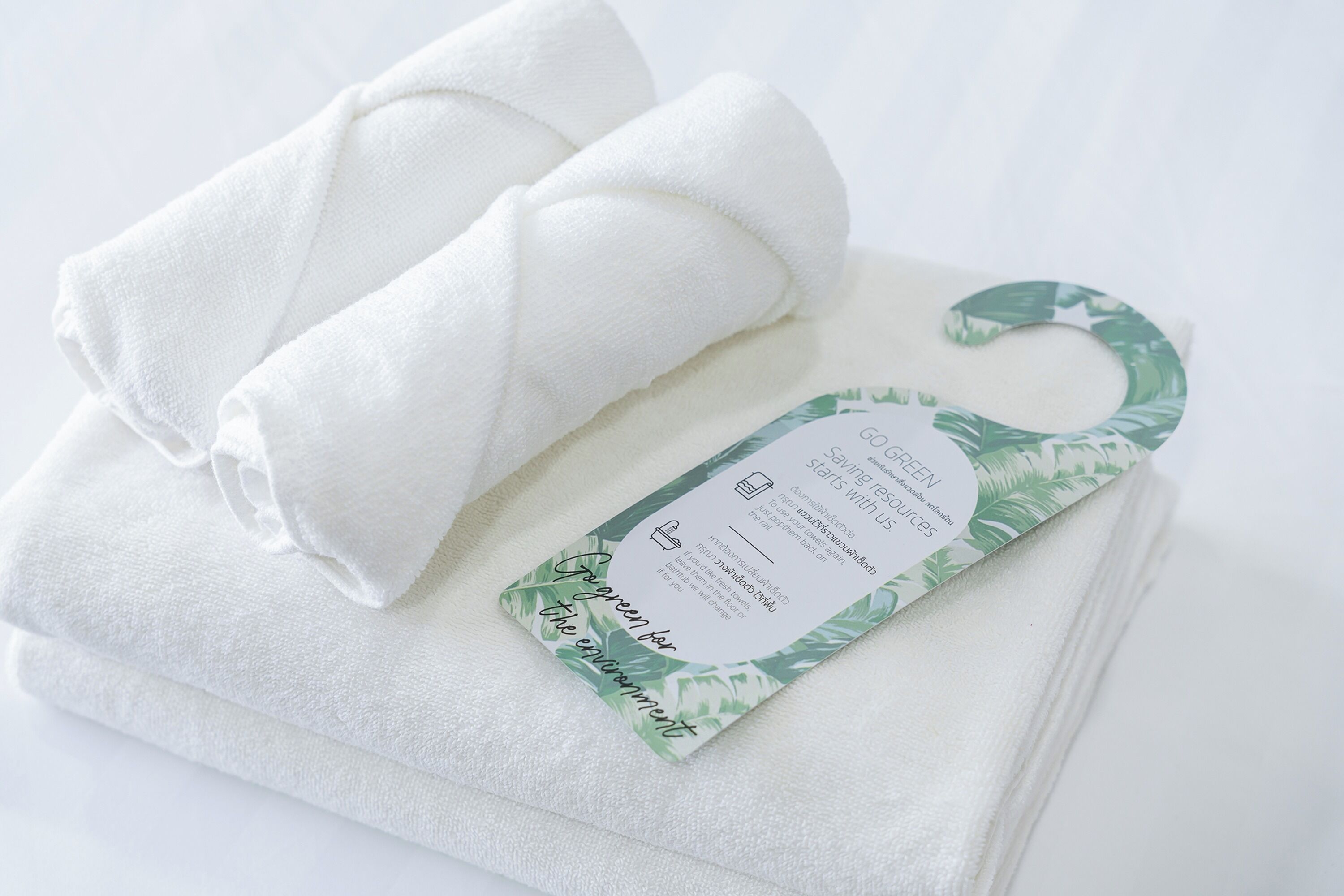 A stack of white towels with a green leaf-patterned tag.