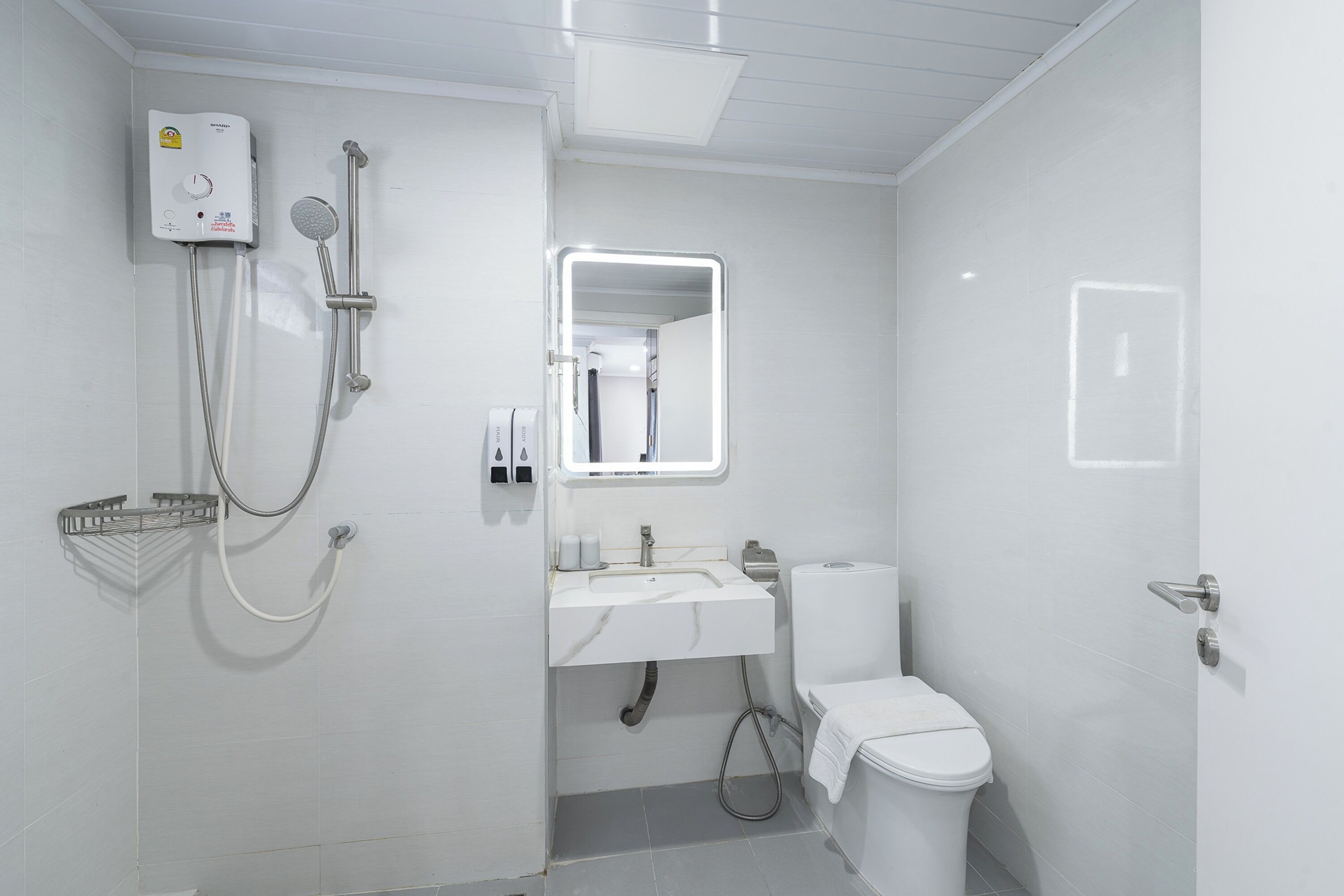 A modern bathroom with a shower, sink, toilet, and a mirror.