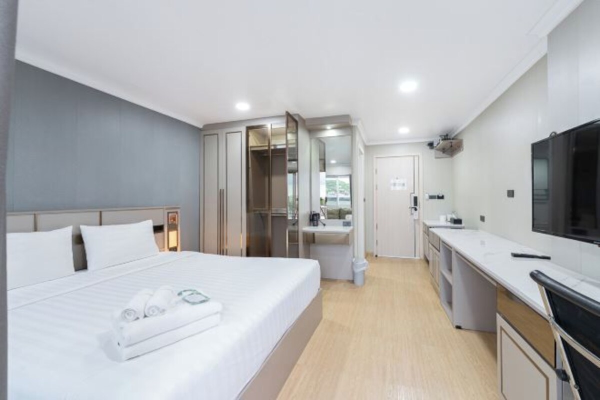 Una habitación de hotel moderna con una cama grande, baño privado, kitchenette y televisor.