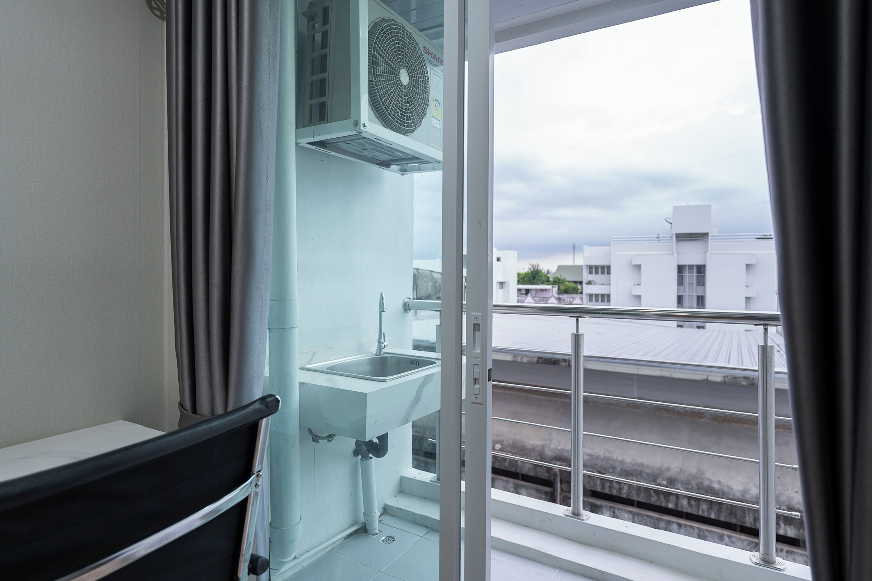 A balcony with a sink, a window, and a view of buildings.