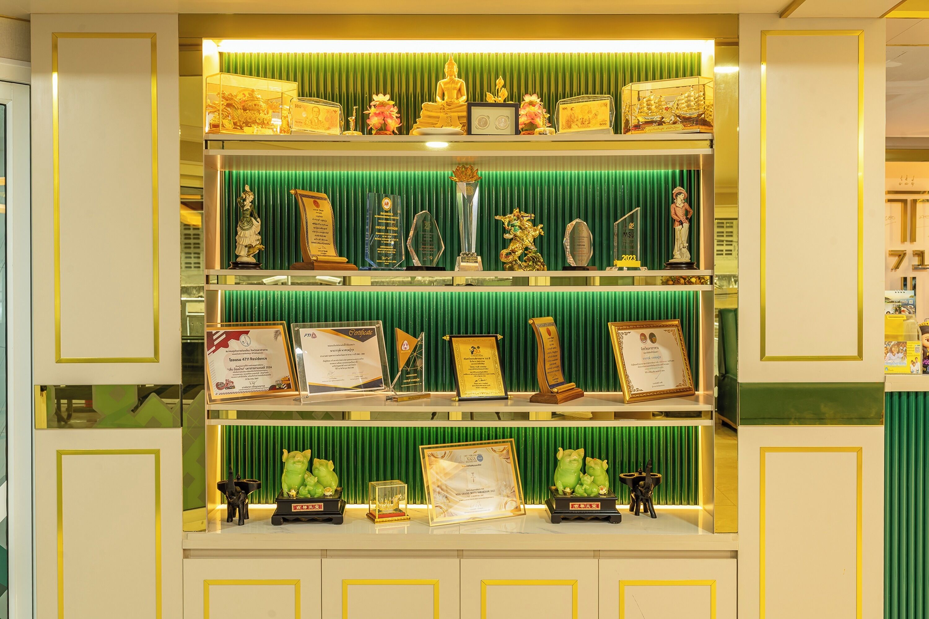 Una exhibición de premios y trofeos en estanterías sobre un fondo verde.