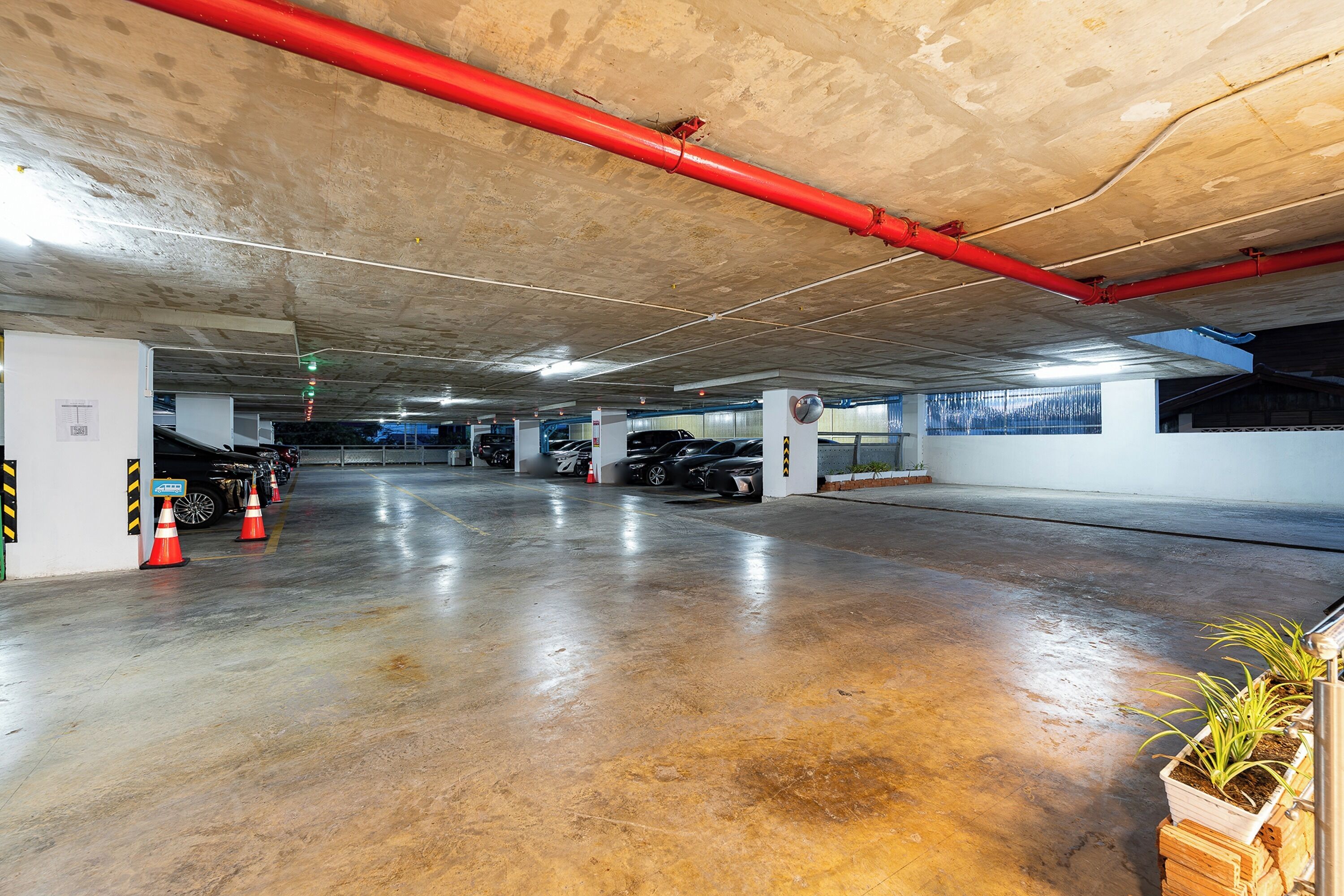 Un estacionamiento de varios niveles con pisos de concreto y tuberías rojas en el techo.