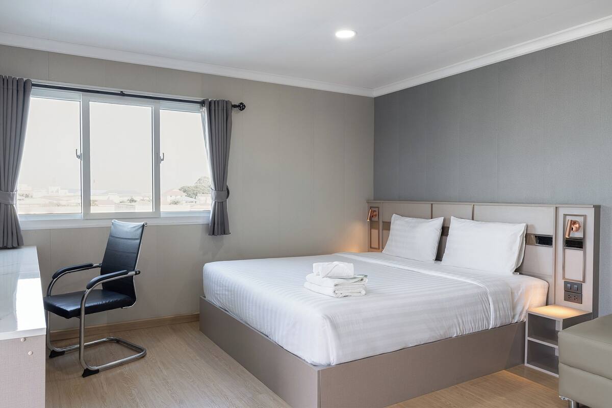 A modern hotel room with a large bed, a desk, and a chair.