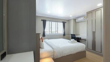 Moderni hotellihuone, jossa on suuri sänky, työpöytä ja vaatekaappi.