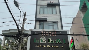 Un edificio de hotel con un letrero que dice "HOTEL L'AIL" y un letrero más pequeño debajo que indica "Sính ra de Phúc v".