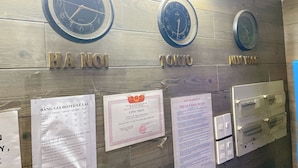 Relojes con nombres de ciudades e información de hoteles sobre una pared de madera.