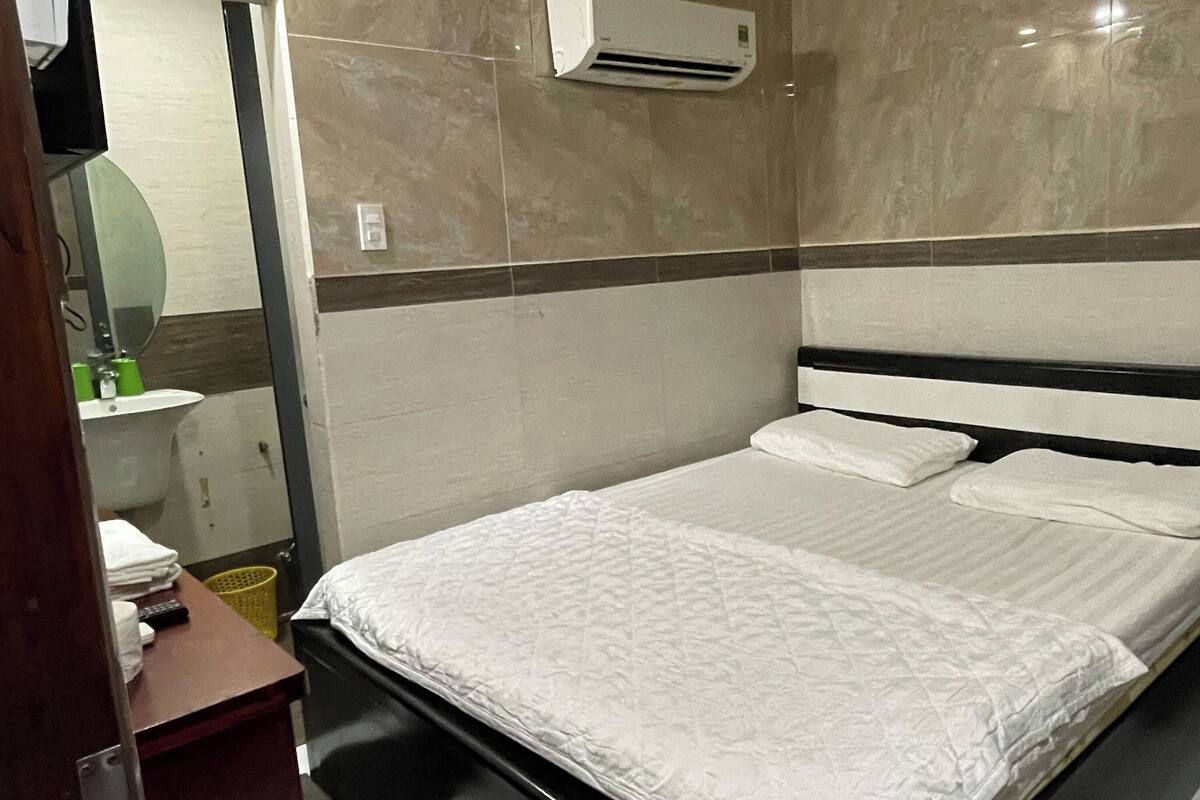 Ein Hotelzimmer mit einem Bett, einem Spiegel, einem Waschbecken und einer Klimaanlage.