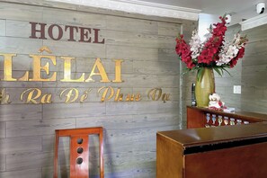 Een hotel receptiebalie met een houten achtergrond en een bord waarop 'HOTEL LELAI' staat.