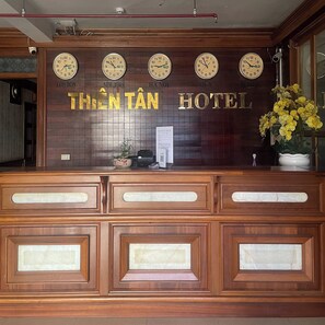 Una recepción con relojes, un arreglo floral y un cartel que dice "THIEN TAN HOTEL".