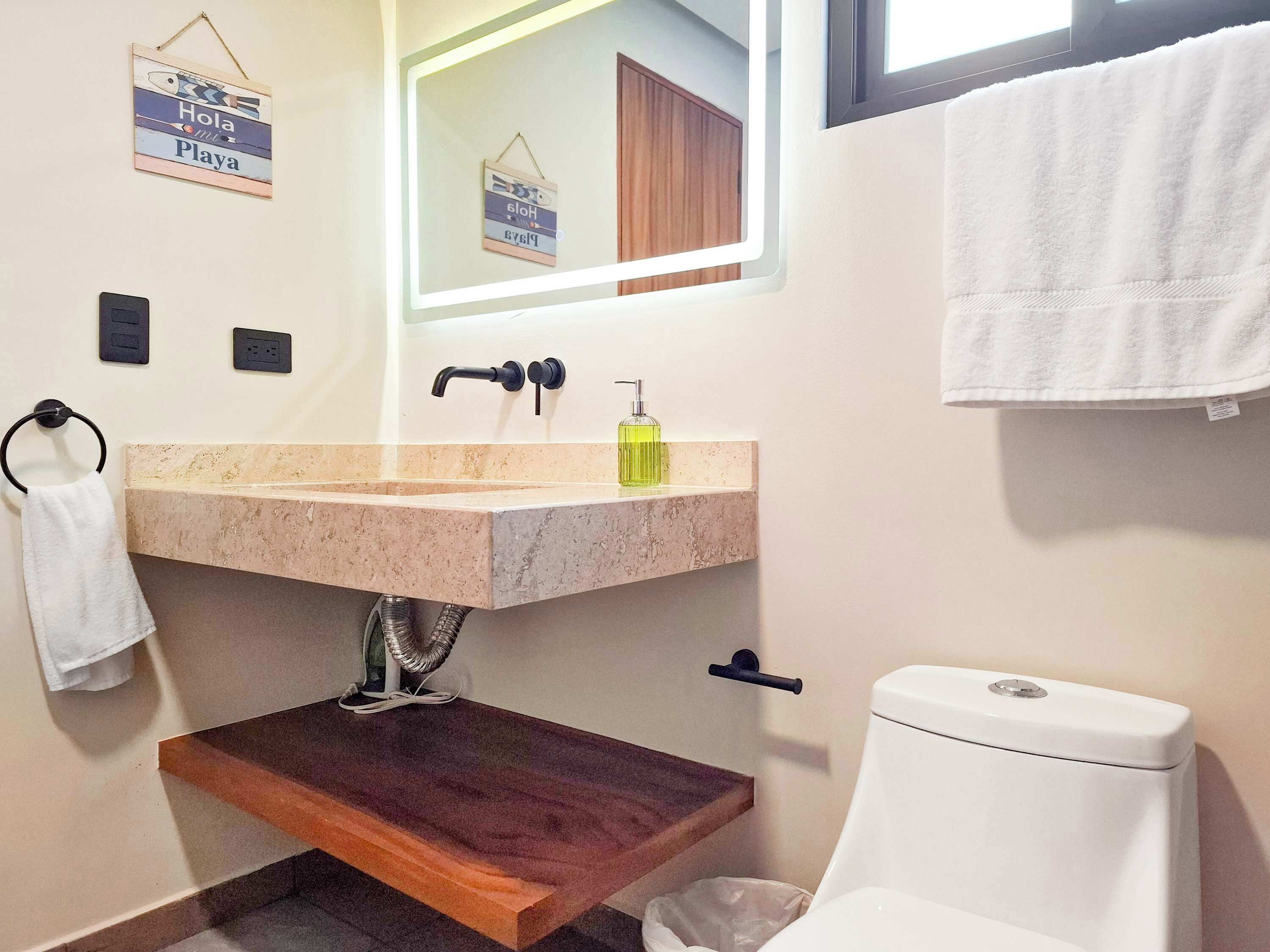 A bathroom with a marble sink, a mirror, a toilet, and a towel rack.