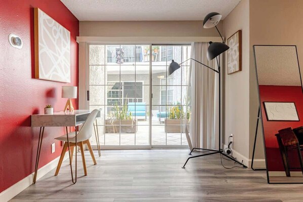 A modern room with a dining area, a large window, and a floor lamp.
