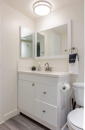 A bathroom with a white vanity, a mirror, a sink, a toilet, and a towel rack with a towel labeled "Makeup".