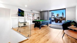A modern living room with a pool table, a sofa, and a dining area.