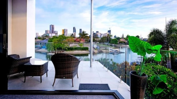 A balcony with wicker furniture, a view of a city skyline, and a river.