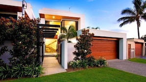 A modern house with a garage, a well-maintained lawn, and a variety of plants.