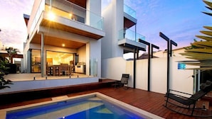 A modern house with a swimming pool, a balcony, and a patio area.