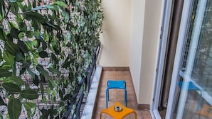 Un petit balcon avec deux chaises et une plante en pot.