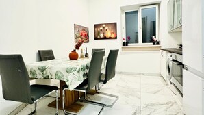 A dining area with a table, chairs, and a vase of flowers. - Comfortable Room for 2, Close to Atzgersdorf (Vienna)