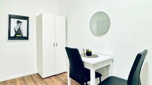 A room with a white wardrobe, a small table with two chairs, a round mirror, and a framed picture on the wall. - Comfortable Room for 2, Close to Atzgersdorf (Vienna)