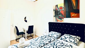 Une chambre à coucher comprenant un lit, deux chaises, un bureau et une œuvre d’art accrochée au mur.