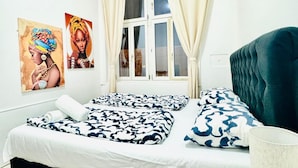 Un dormitorio con dos camas, una ventana con cortinas y dos cuadros en las paredes.
