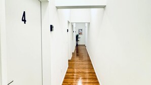 Un pasillo con suelo de madera, paredes blancas y una puerta con el número 4.