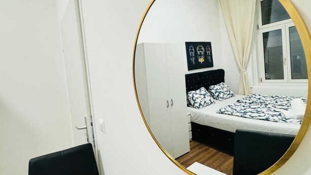 A bedroom with a bed, a wardrobe, a mirror, and a window with curtains. - Beautiful Room Close to Atzgersdorf (Vienna)