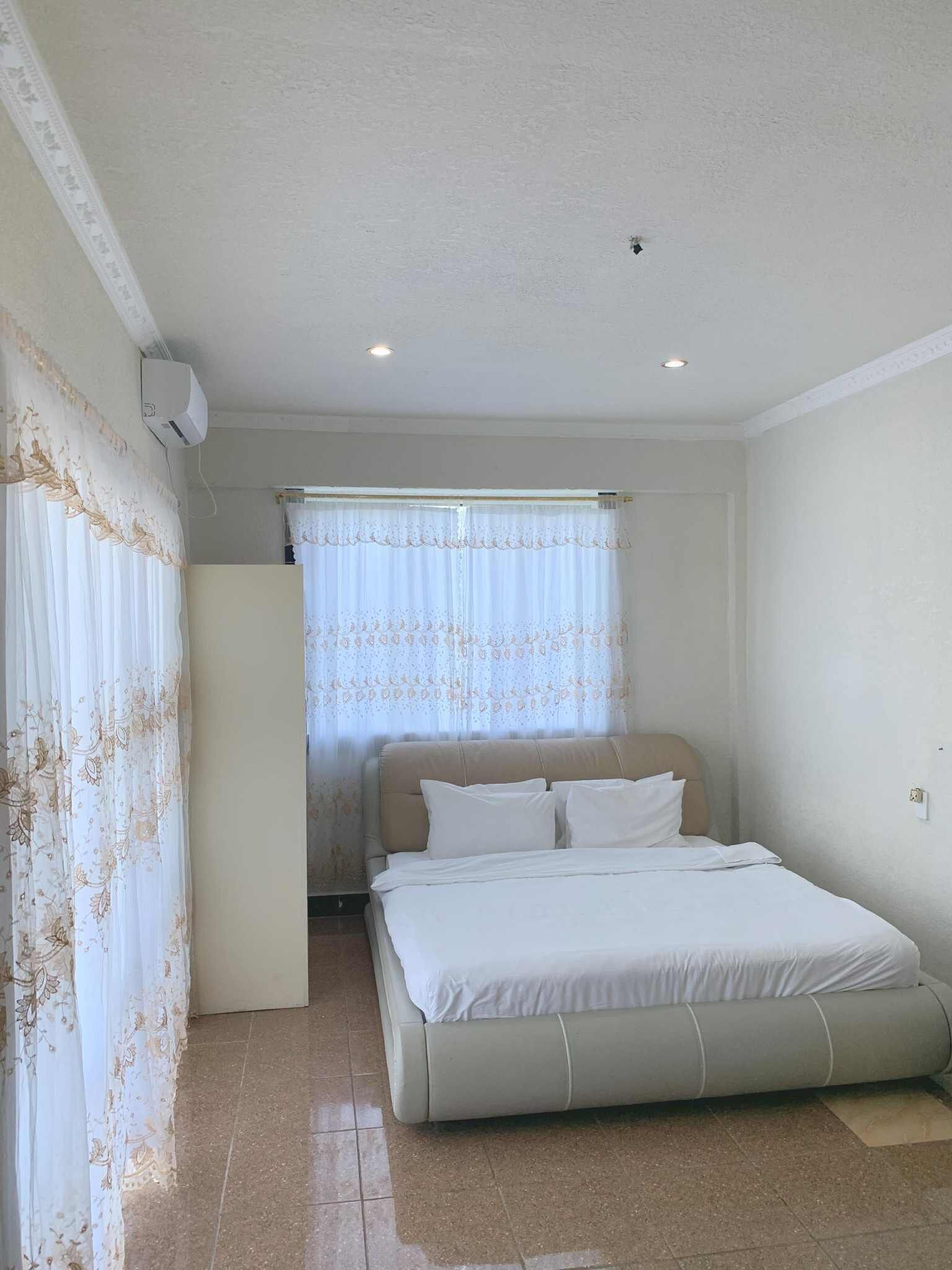 A bedroom with a bed, curtains, and a ceiling fan.
