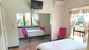 Et hotelværelse med en seng, et lille bord med stole, et fjernsyn og en aircondition.