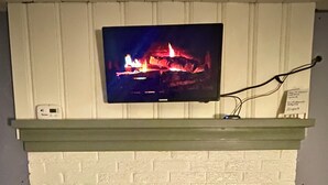 A white brick fireplace with a TV mounted above it. - Ranch House in peaceful Little Hocking close to the Ohio River. Heat/AC, WiFi (Little Hocking)