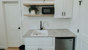 A compact kitchen with a built-in microwave, a sink, and a dishwasher. - Cozy Casita (Price)