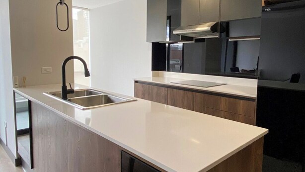 A modern kitchen with a central island, dark wood cabinets, and a stainless steel sink.