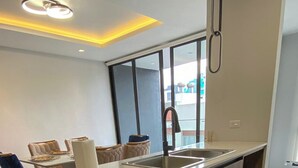 A modern kitchen with a dishwasher, a sink, and a window overlooking a cityscape.
