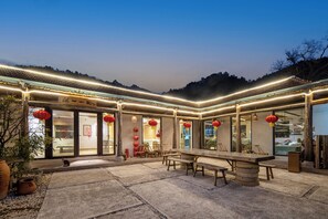 Un espace extérieur aménagé pour les repas, avec une longue table en bois et des bancs, entouré d’une cour pavée de pierres.