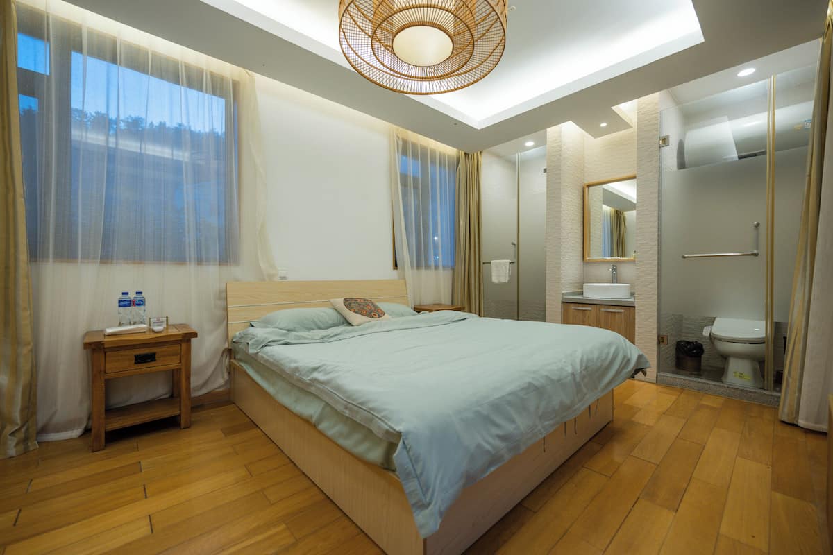 Un dormitorio moderno con una cama grande, mesitas de noche y un baño con inodoro y ducha.