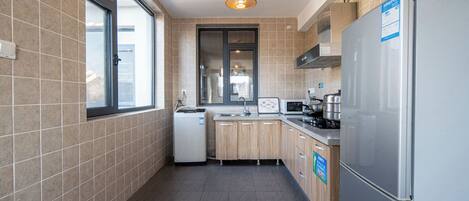 A modern kitchen with a refrigerator, stove, microwave, and wooden cabinets.