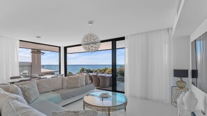 Ein modernes Wohnzimmer mit einem großzügigen Ecksofa, einem Glastisch und Meerblick.