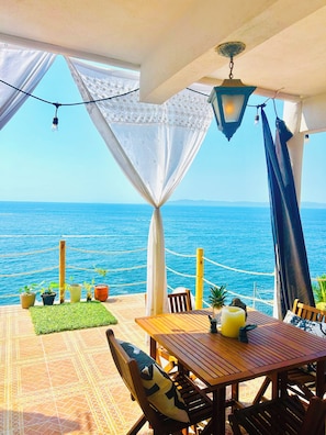 Enjoy a tranquil ocean view from this outdoor seating area, featuring a table, chairs, and lush greenery.